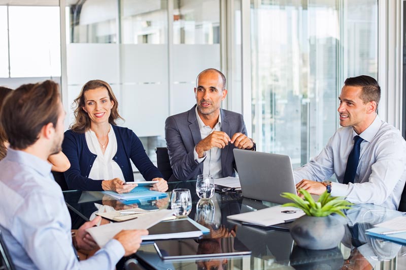 A business group chatting in an office with a plant on the table