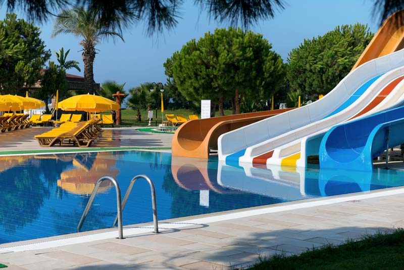 An outside pool with slides, yellow chairs and yellow umbrellas